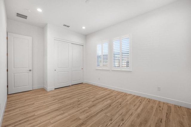 unfurnished bedroom with light hardwood / wood-style flooring and a closet