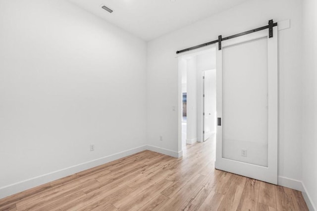 unfurnished room featuring a barn door and light wood-type flooring