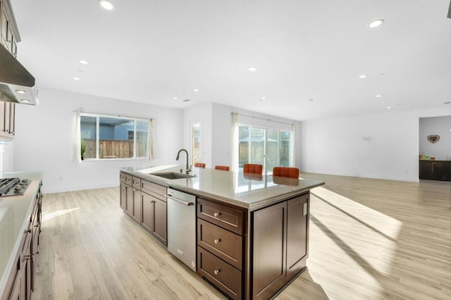 kitchen featuring sink, stainless steel appliances, extractor fan, a center island with sink, and light wood-type flooring