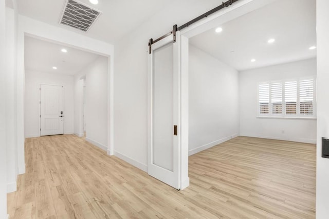 corridor featuring a barn door and light wood-type flooring