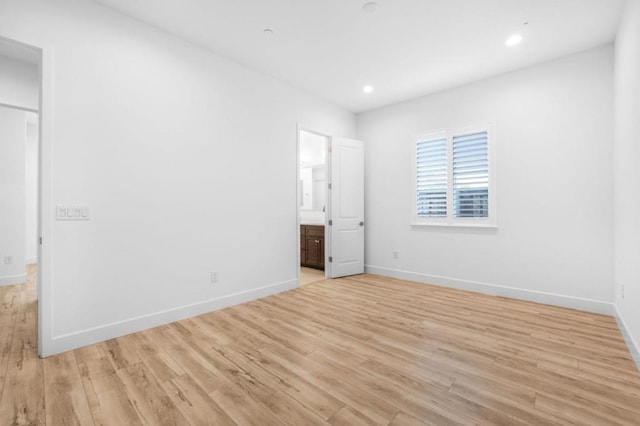 unfurnished bedroom with ensuite bathroom and light wood-type flooring