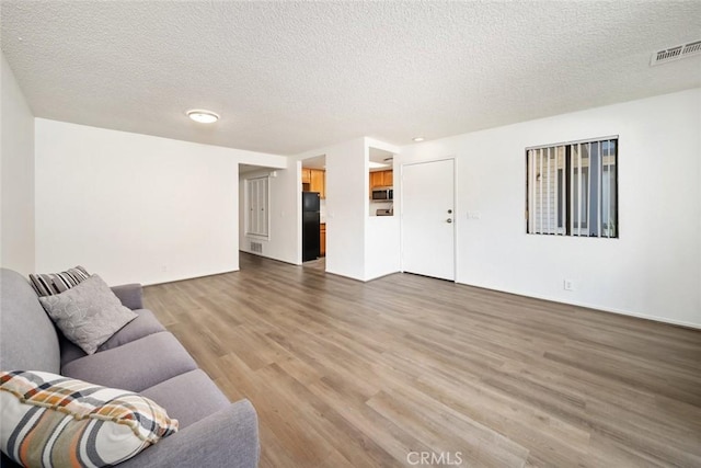 unfurnished living room featuring hardwood / wood-style floors and a textured ceiling