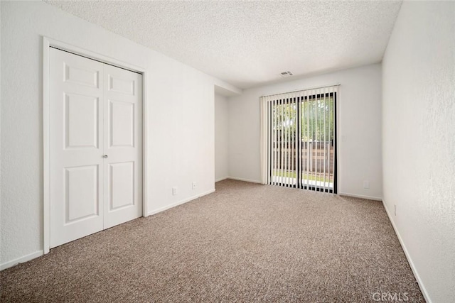 carpeted empty room featuring a textured ceiling