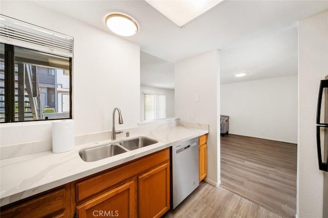 kitchen with sink, light hardwood / wood-style flooring, light stone countertops, and stainless steel dishwasher