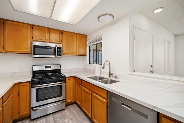 kitchen with sink, stainless steel appliances, and light hardwood / wood-style floors