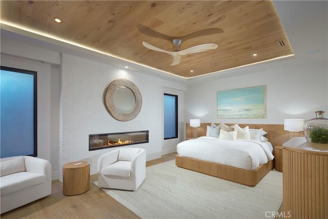 bedroom featuring hardwood / wood-style floors, wood ceiling, ceiling fan, wood walls, and a tray ceiling