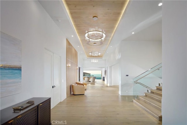 hallway with wooden ceiling, light hardwood / wood-style flooring, and a raised ceiling