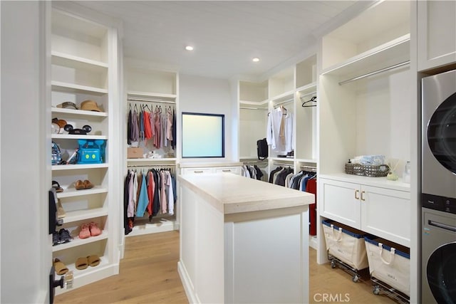 spacious closet featuring light wood-type flooring and stacked washer / drying machine