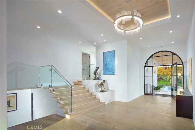 interior space with hardwood / wood-style flooring, a notable chandelier, and a raised ceiling