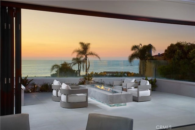 patio terrace at dusk with a water view and an outdoor fire pit