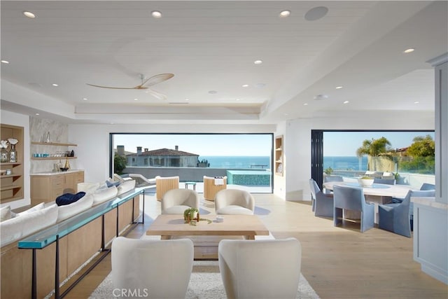 living room featuring built in features, a water view, a tray ceiling, wooden ceiling, and light hardwood / wood-style floors