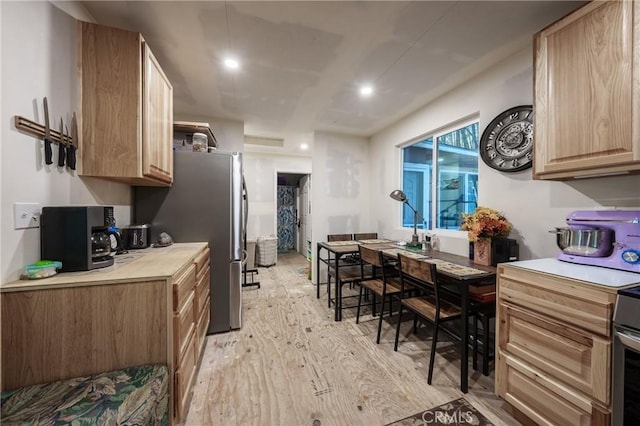 kitchen with light brown cabinets, light hardwood / wood-style flooring, and stainless steel fridge