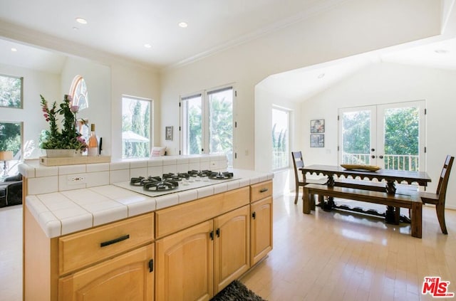 kitchen featuring tile countertops, white gas cooktop, light hardwood / wood-style floors, a healthy amount of sunlight, and french doors