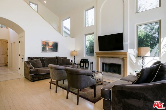 living room featuring a towering ceiling, a tiled fireplace, and light hardwood / wood-style floors