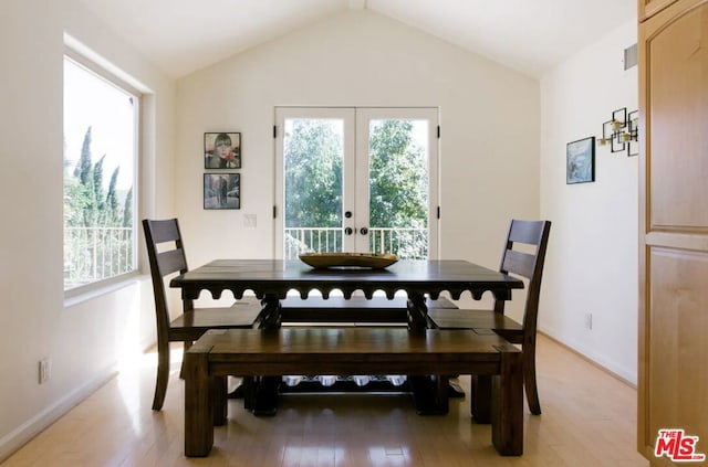 dining room featuring lofted ceiling, light hardwood / wood-style flooring, and french doors