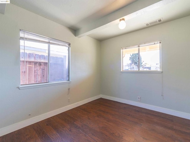 empty room featuring dark wood-type flooring and beam ceiling