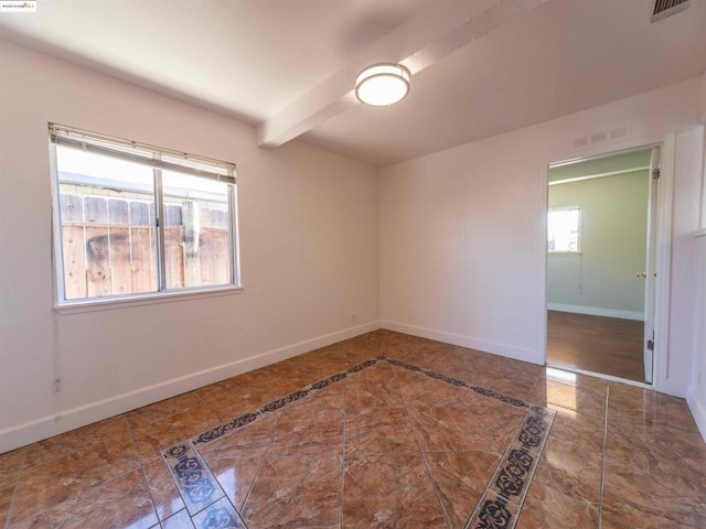 tiled spare room with beamed ceiling