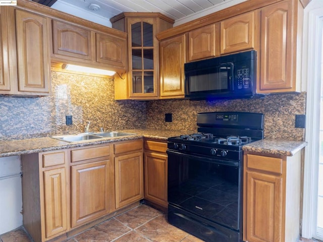 kitchen featuring light stone countertops, black appliances, tile patterned floors, decorative backsplash, and sink