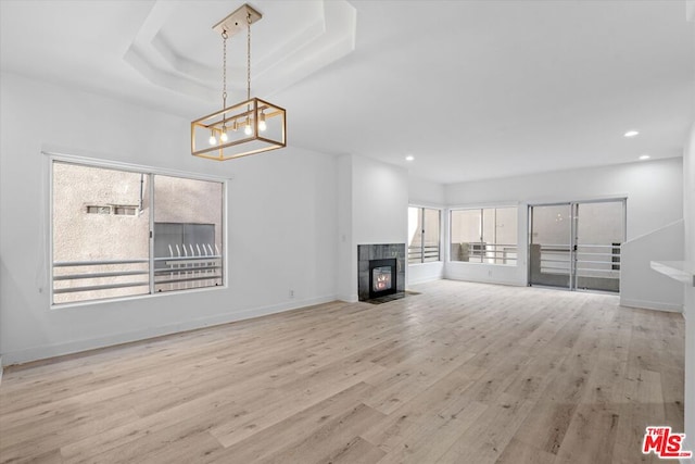 unfurnished living room with a tray ceiling, light hardwood / wood-style flooring, and a fireplace