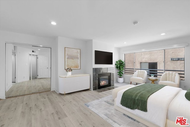 bedroom with light hardwood / wood-style floors and a tile fireplace