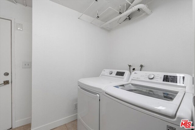 laundry room with washing machine and dryer and light tile patterned floors