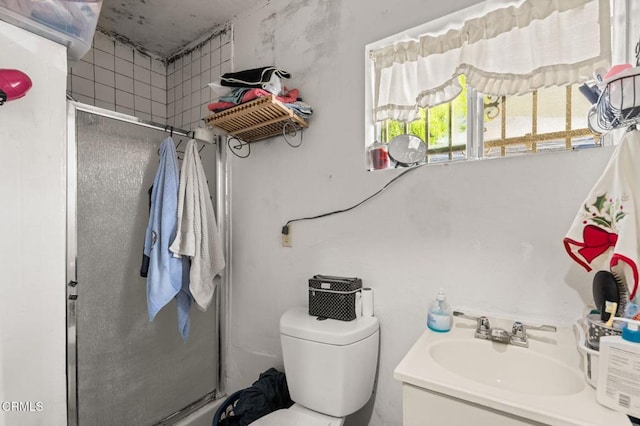 bathroom with a shower with shower door, toilet, and vanity