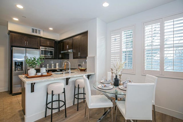 kitchen featuring stainless steel appliances, sink, dark brown cabinets, and plenty of natural light