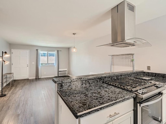 kitchen with white cabinetry, hanging light fixtures, dark stone countertops, stainless steel range with gas cooktop, and island exhaust hood