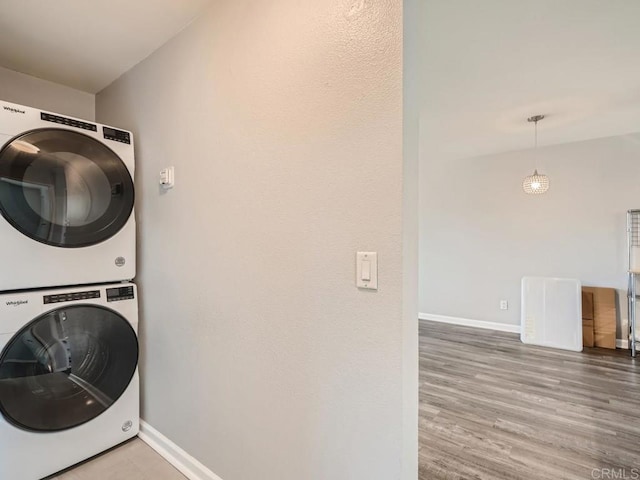 clothes washing area with hardwood / wood-style flooring and stacked washer and clothes dryer