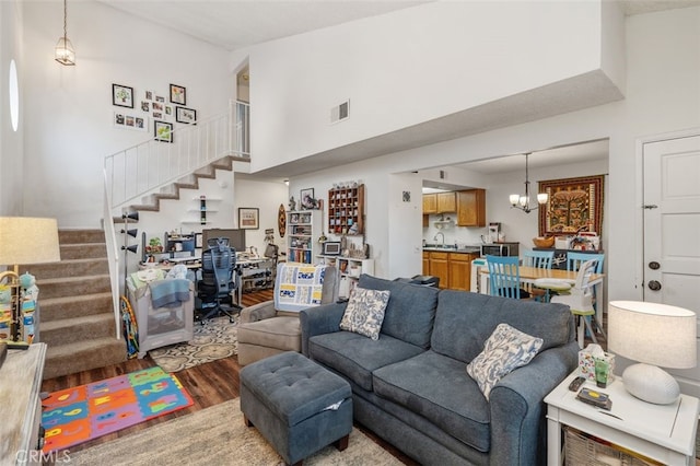 living room featuring sink, a chandelier, hardwood / wood-style floors, and a high ceiling