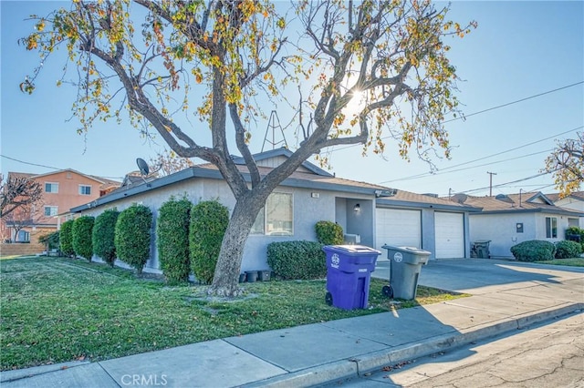 view of front facade featuring driveway, a garage, a front yard, and stucco siding