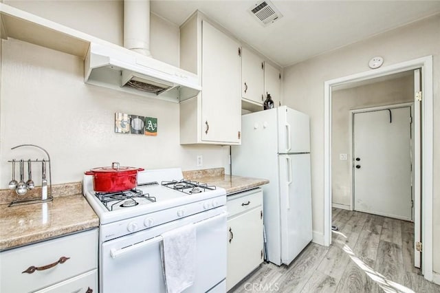 kitchen featuring white appliances, wall chimney range hood, light wood-style flooring, and light countertops