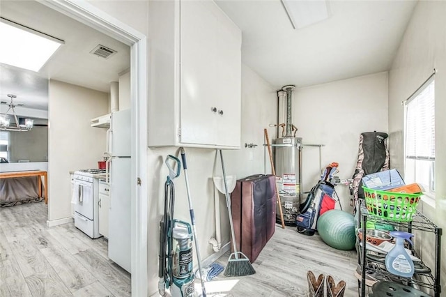 workout room with gas water heater, light wood-style flooring, and a skylight