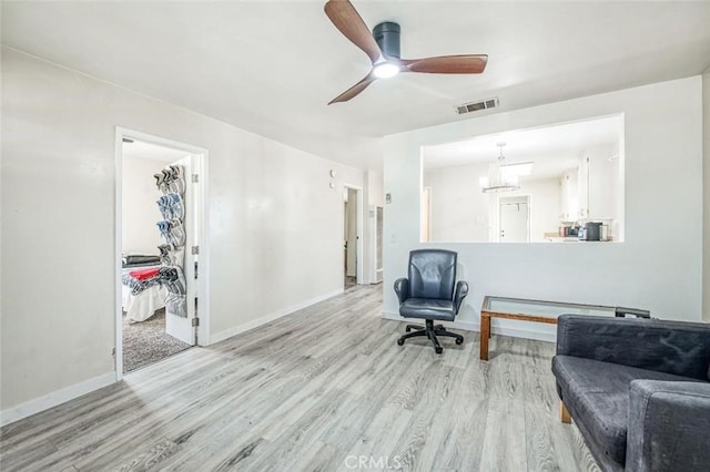 living area featuring wood finished floors, a chandelier, baseboards, and a ceiling fan