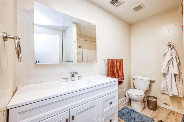 bathroom featuring toilet, wood finished floors, vanity, and baseboards