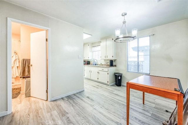 kitchen featuring light wood finished floors, a chandelier, white cabinetry, and light countertops