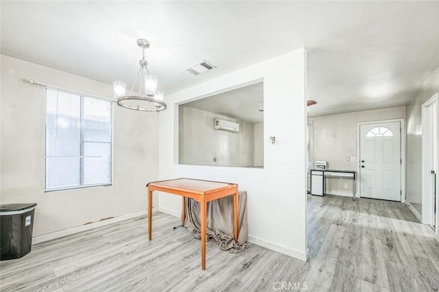 dining area featuring wood finished floors, a wall unit AC, a chandelier, and baseboards