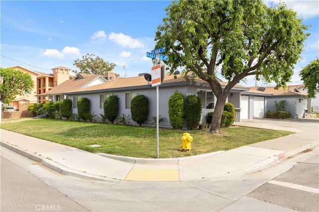 ranch-style house with driveway, a front yard, a garage, and stucco siding