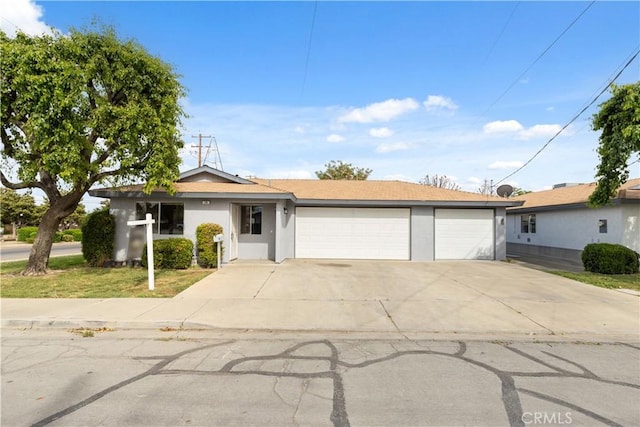 ranch-style home with stucco siding, concrete driveway, an attached garage, and solar panels