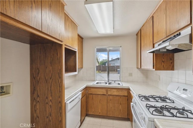 kitchen with white appliances, tile countertops, backsplash, and under cabinet range hood