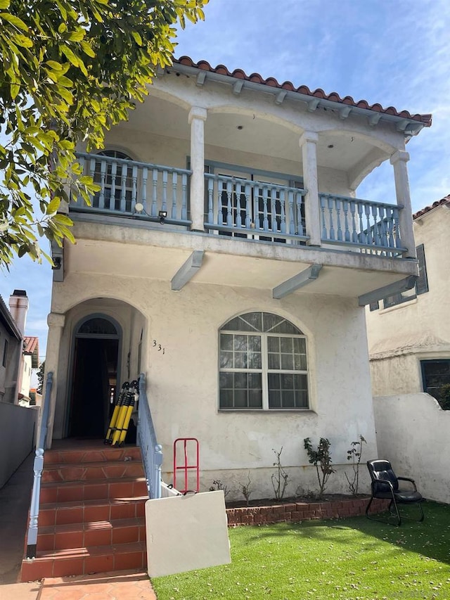 view of front of home with a balcony and a front lawn