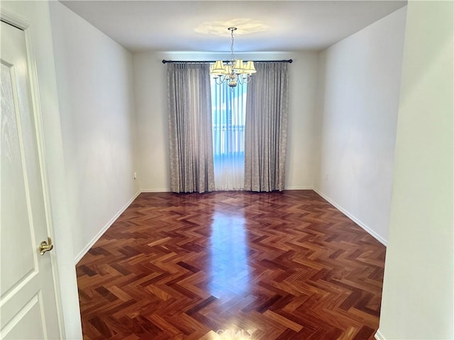 empty room featuring an inviting chandelier and dark parquet flooring