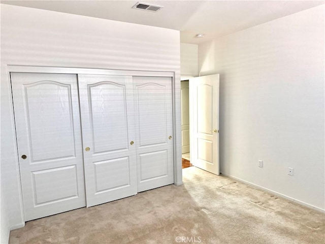 unfurnished bedroom featuring light colored carpet and a closet