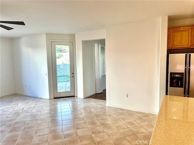 tiled empty room featuring ceiling fan