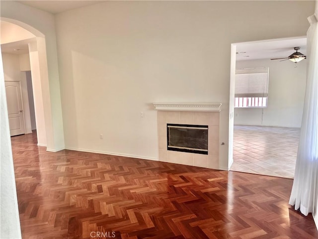 unfurnished living room with parquet flooring, ceiling fan, and a fireplace