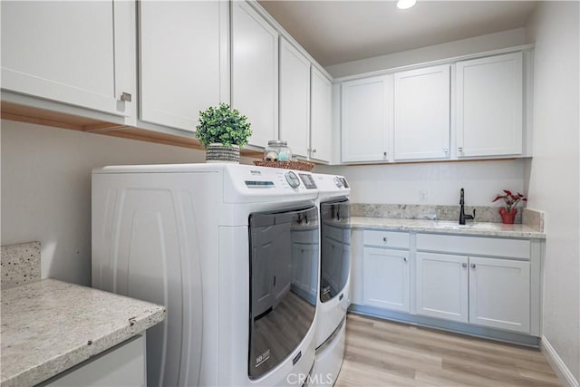 laundry room featuring sink, light hardwood / wood-style flooring, cabinets, and independent washer and dryer