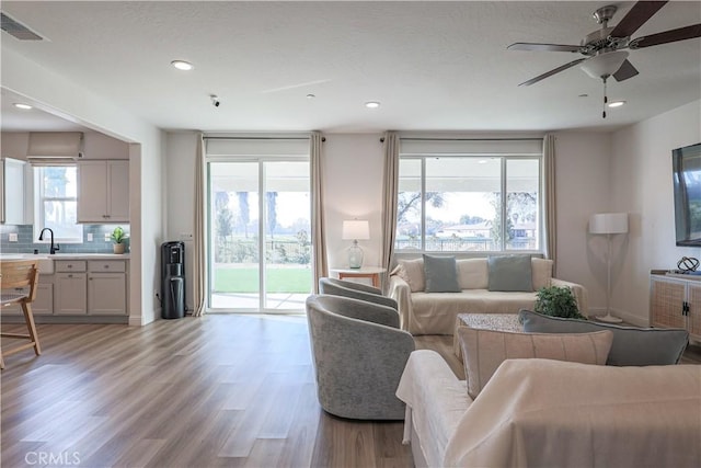 living room with sink, light hardwood / wood-style floors, and ceiling fan