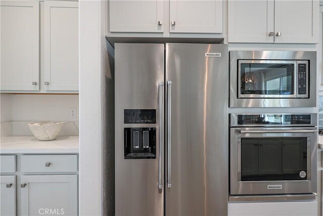 kitchen with light stone countertops, white cabinetry, and stainless steel appliances