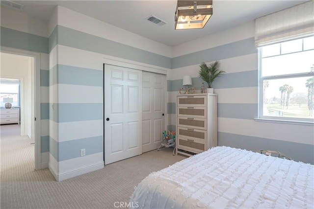 bedroom featuring a closet, light colored carpet, and multiple windows