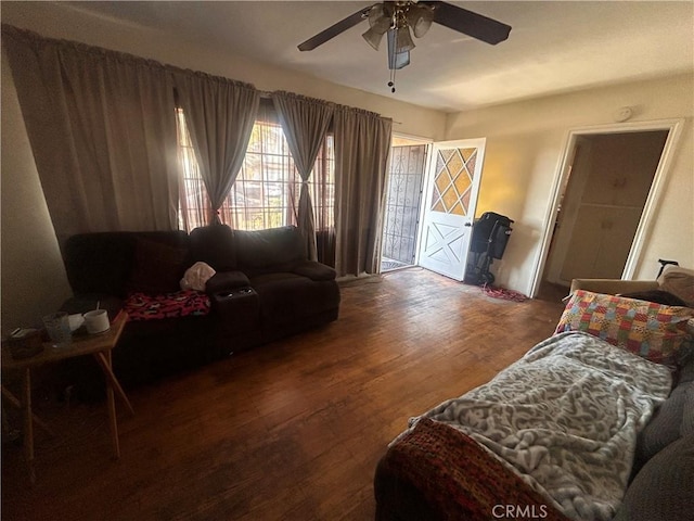 living room featuring dark wood-type flooring and ceiling fan